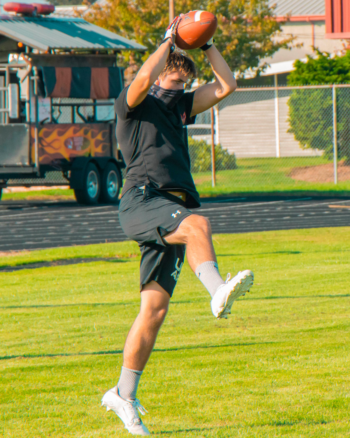 A player sports a mask while catching footballs Wednesday afternoon at Napavine High School.