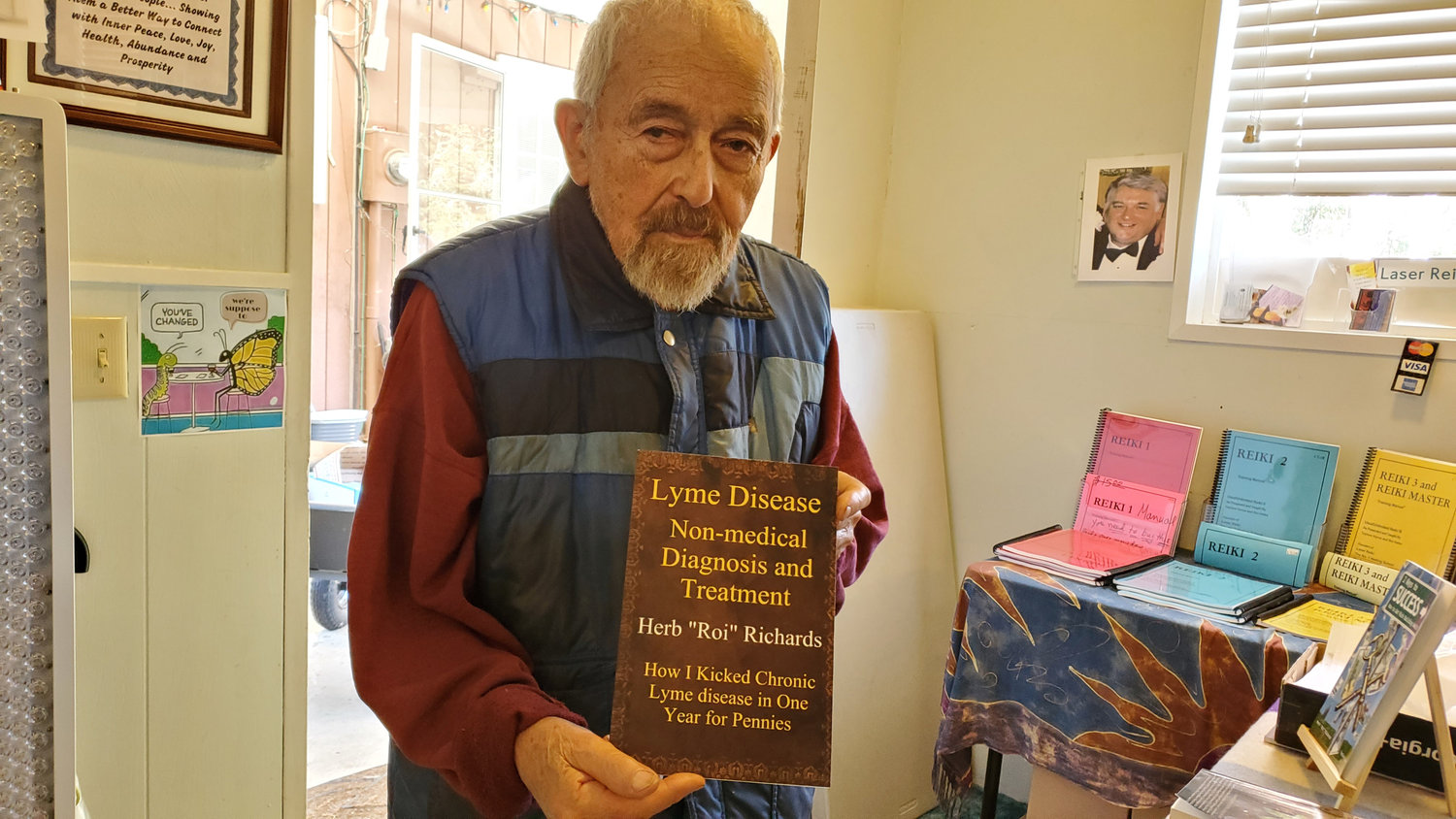 Reiki Ranch Energy Healing School co-owner Roi Vance, 91, holding the a book he authored on overcoming lyme disease through Reiki healing.