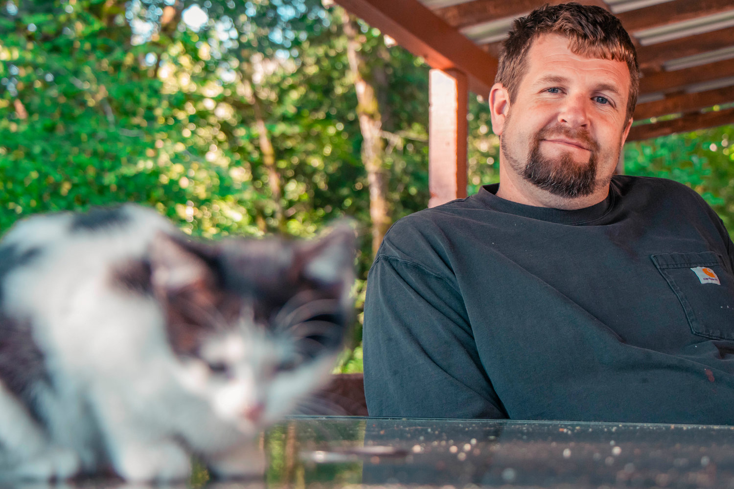Blake Bennett smiles as he watches a kitten play on an outdoor table Thursday morning at his Salkum residence.