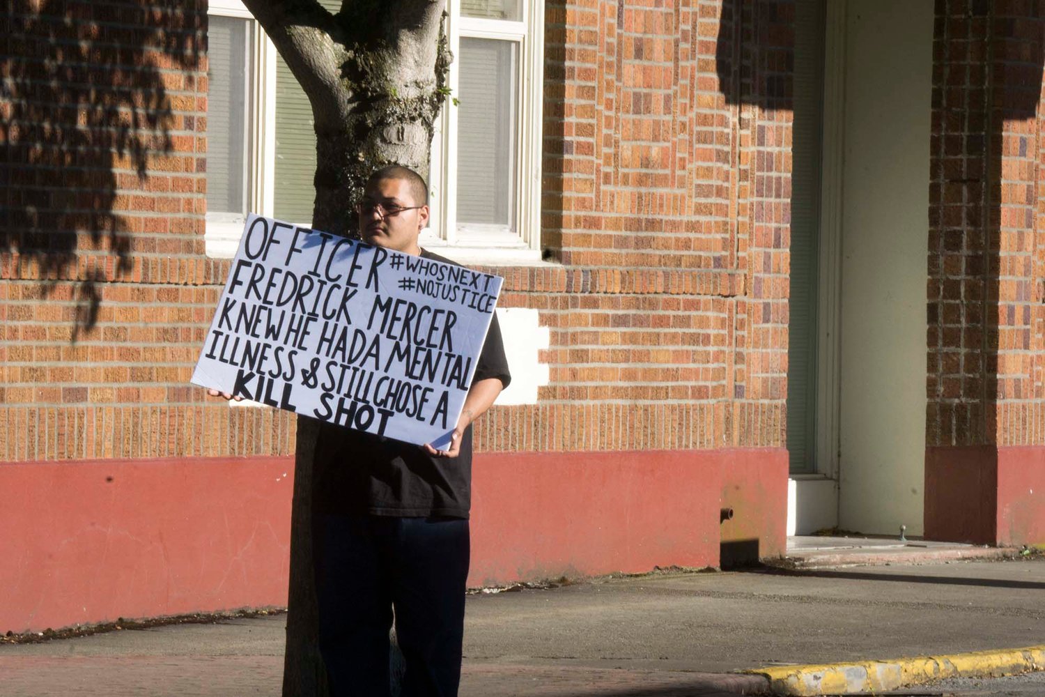 A man holds a sign that calls out Centralia Police officer Fredrick Mercer.