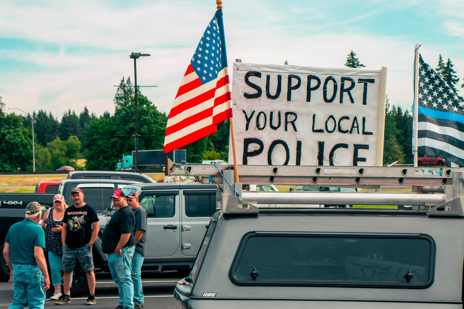 A sign that reads ’Support Your Local Police’ sits on a truck with flags as it pulls through the parking lot of Bethel Church Tuesday afternoon in south Chehalis.