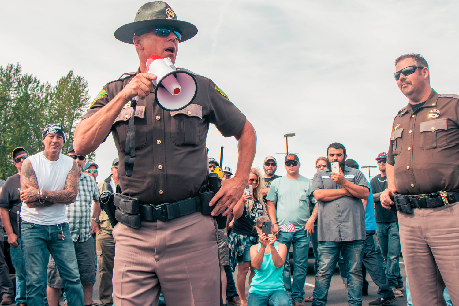Sheriff Rob Snaza speaks with a microphone to Hamilton sign supporters in the parking lot of Bethel Church Tuesday afternoon in south Chehalis.