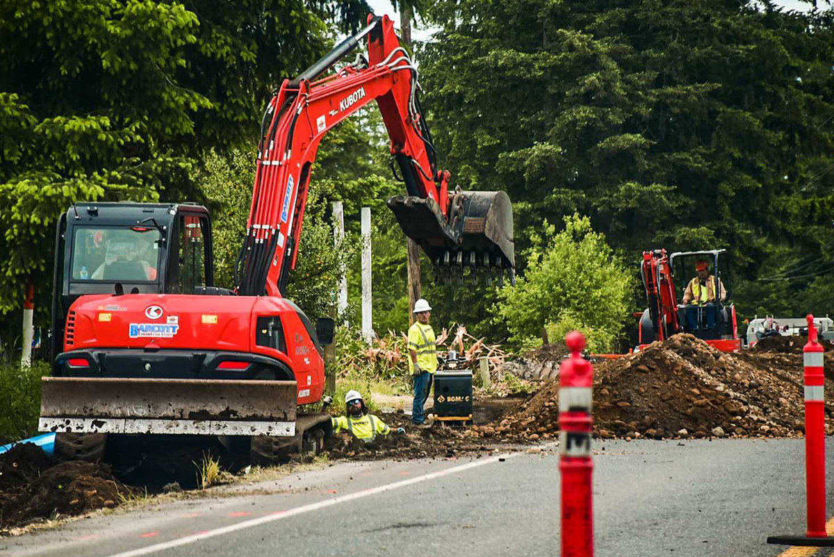 Construction crews use machinery to dig a ditch alongside Old Highway 99 SE in Tenino Tuesday afternoon.