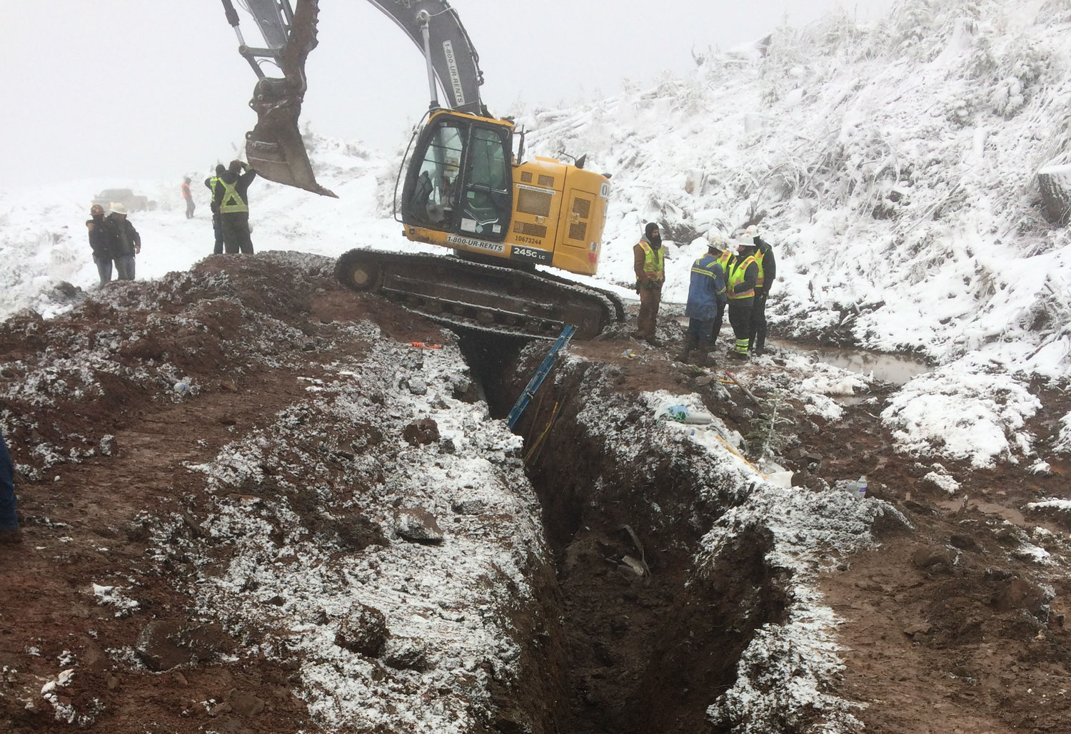 An escavator straddles the trench where two contractors were buried in a trench collapse. Records from the Thurston County Sheriff’s Office estimate the maximum depth of the trench to be around 12 feet deep.