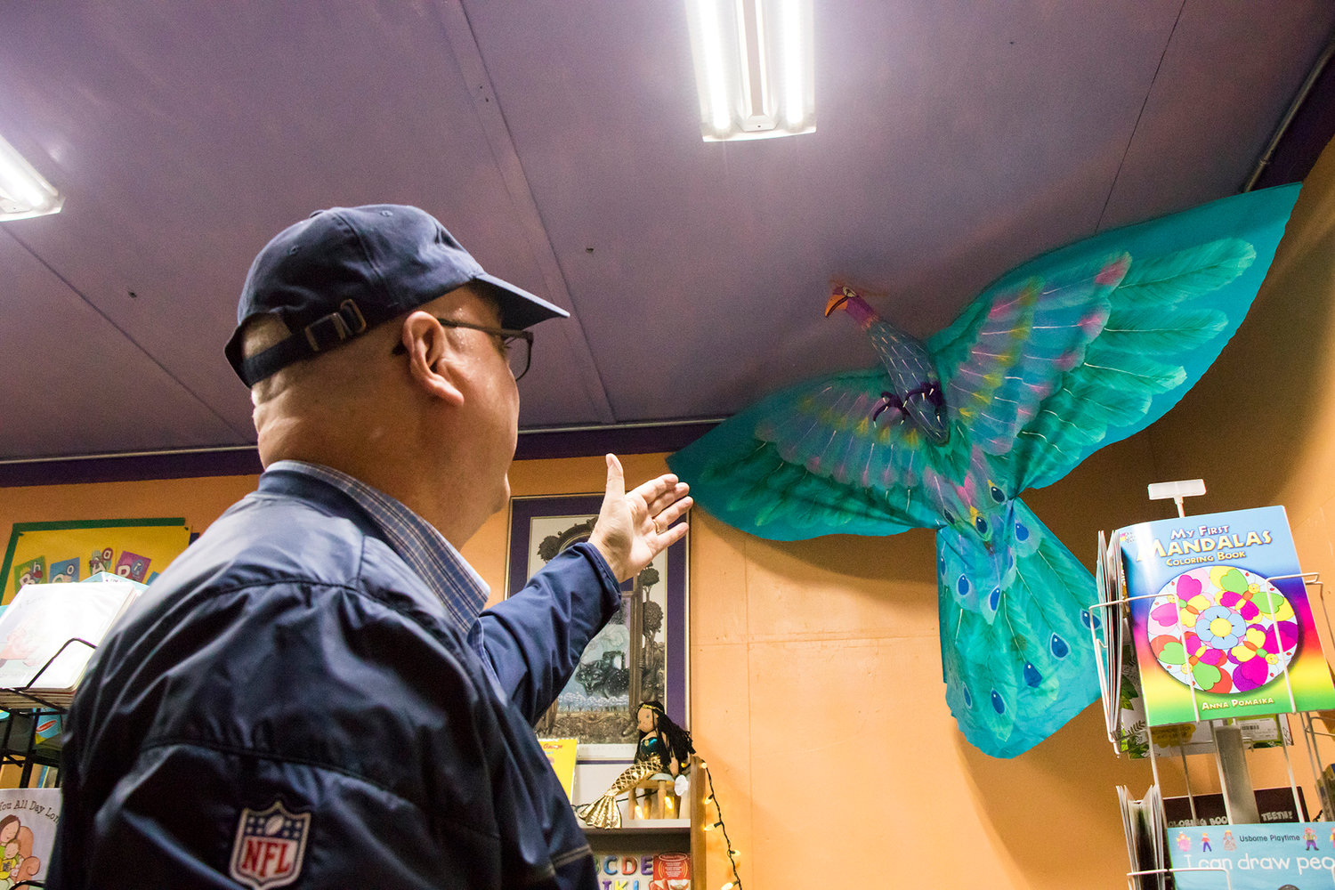 Owner David Hartz points to a Peacock display inside Book 'N' Brush Friday afternoon in Chehalis.