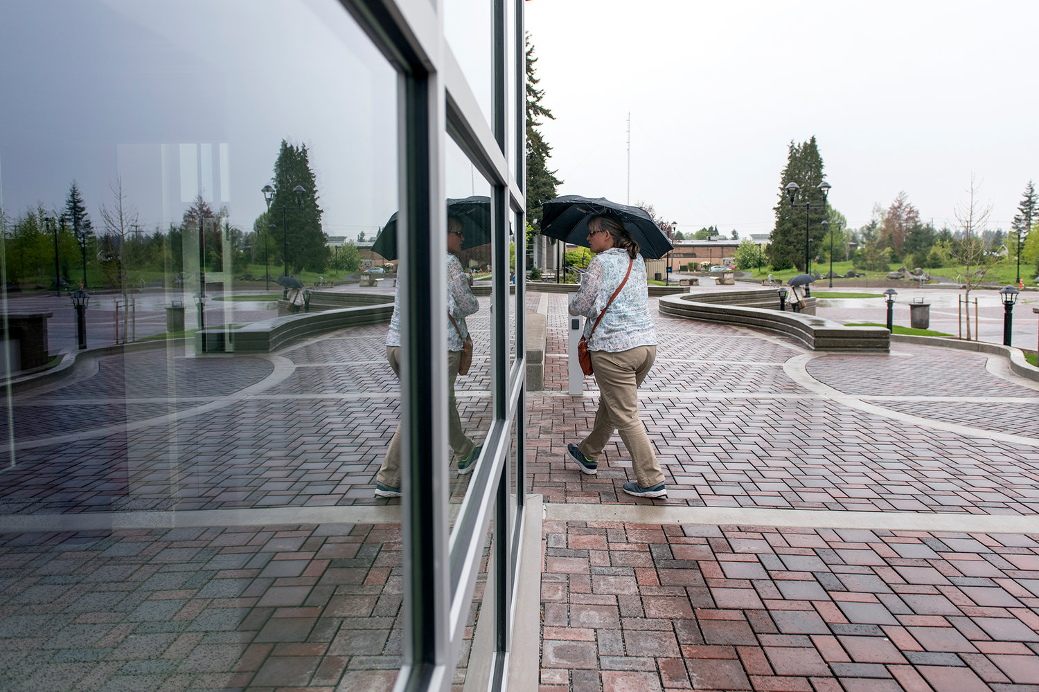 A woman with an umbrella walks into the northwest entrance to the TransAlta Student Commons building for the grand opening on the Centralia College campus in May 2017. 