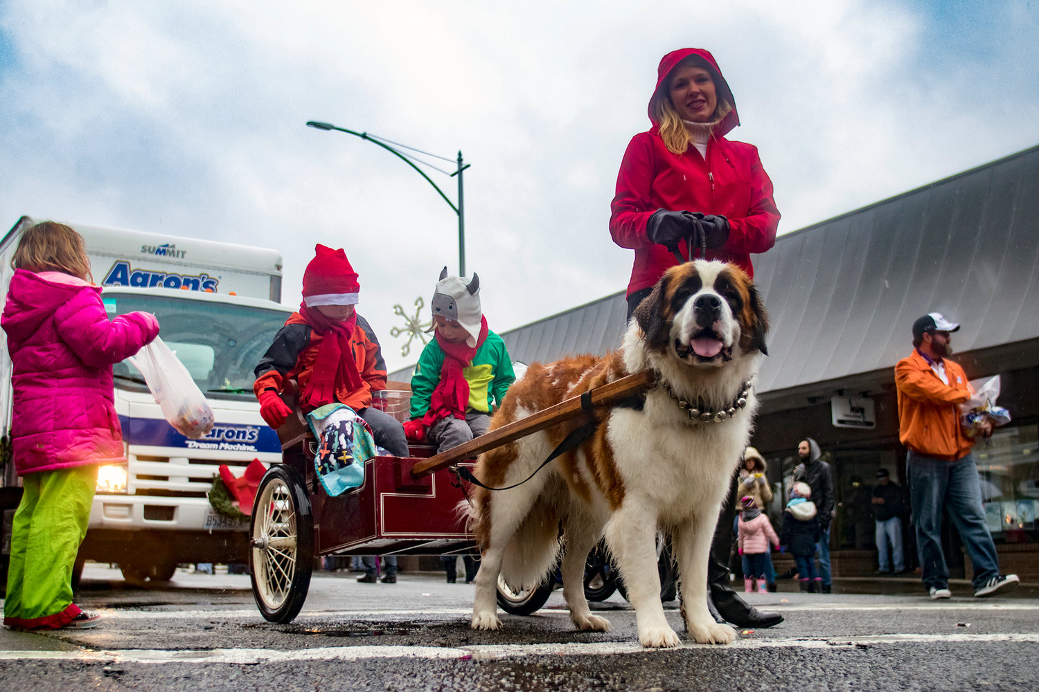 A girl swings her bag of candy as a dog pulls two children in a carriage during the annual Santa Parade last year in downtown Chehalis.