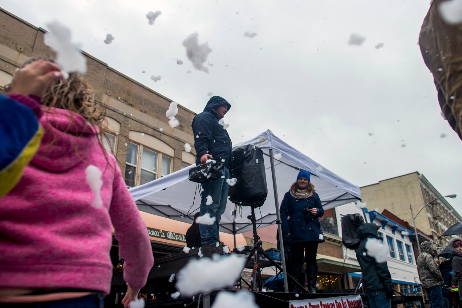 Kids play in foam snow as a man uses a snow machine during the annual Santa Parade Saturday morning in downtown Chehalis.