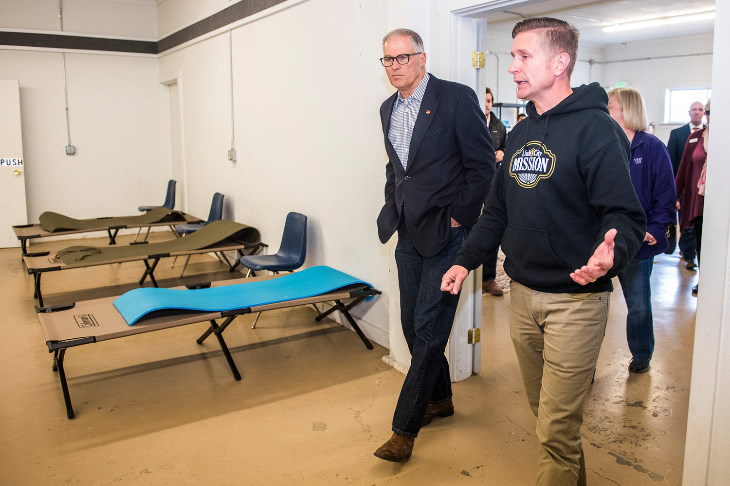 FILE PHOTO — Governor Jay Inslee, left, talks with Director Josh Gering, right, of Bethel Church's Hub City Mission at the cold weather shelter inside the Southwest Washington Fairgrounds in Chehalis in 2019.