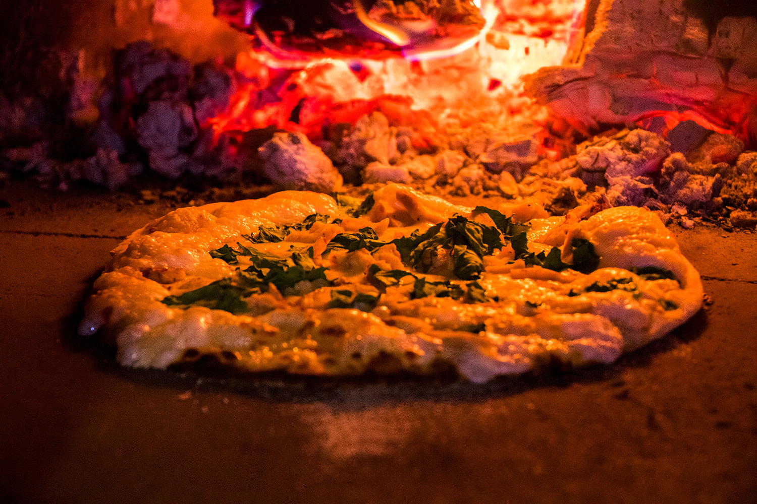 A garlic chicken pizza cooks in a wood fire oven inside the Milltown Pizza food cart Tuesday afternoon in Chehalis.