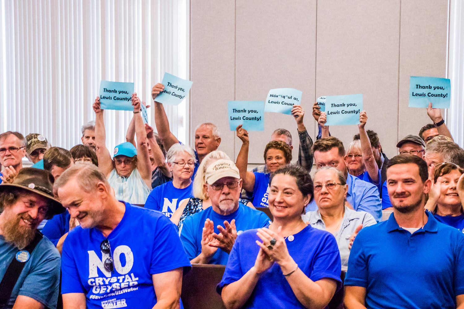 Lewis County Water Alliance members and supporters cheer and hold signs after a decision to issue a moratorium to block Crystal Geyser was made in favor of the group during a public meeting with county commissioners Monday morning at the Lewis County Historical Courthouse in Chehalis.