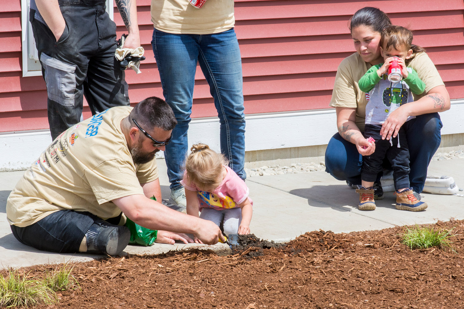 Jereme Sawyer, left, makes a new friend while doing some landscaping during a community volunteer day at the adapted house being built for him by national nonprofit Homes For Our Troops.