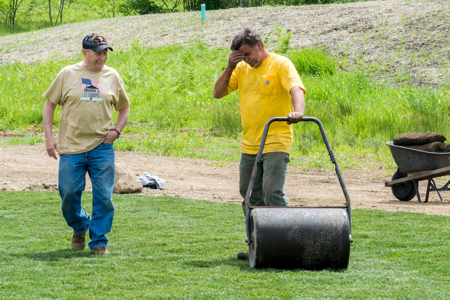 Travis Nichelson, left, chats with a member of the work crew that installed nearly 6,000 square feet of sod Saturday morning at the soon-to-be Tenino home of wounded veteran Jereme Sawyer.