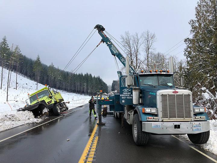 Tow crews work to pull a Washington State Department of Transportation snowplow out of a ditch between Morton and Mineral on state Route 7 Wednesday.