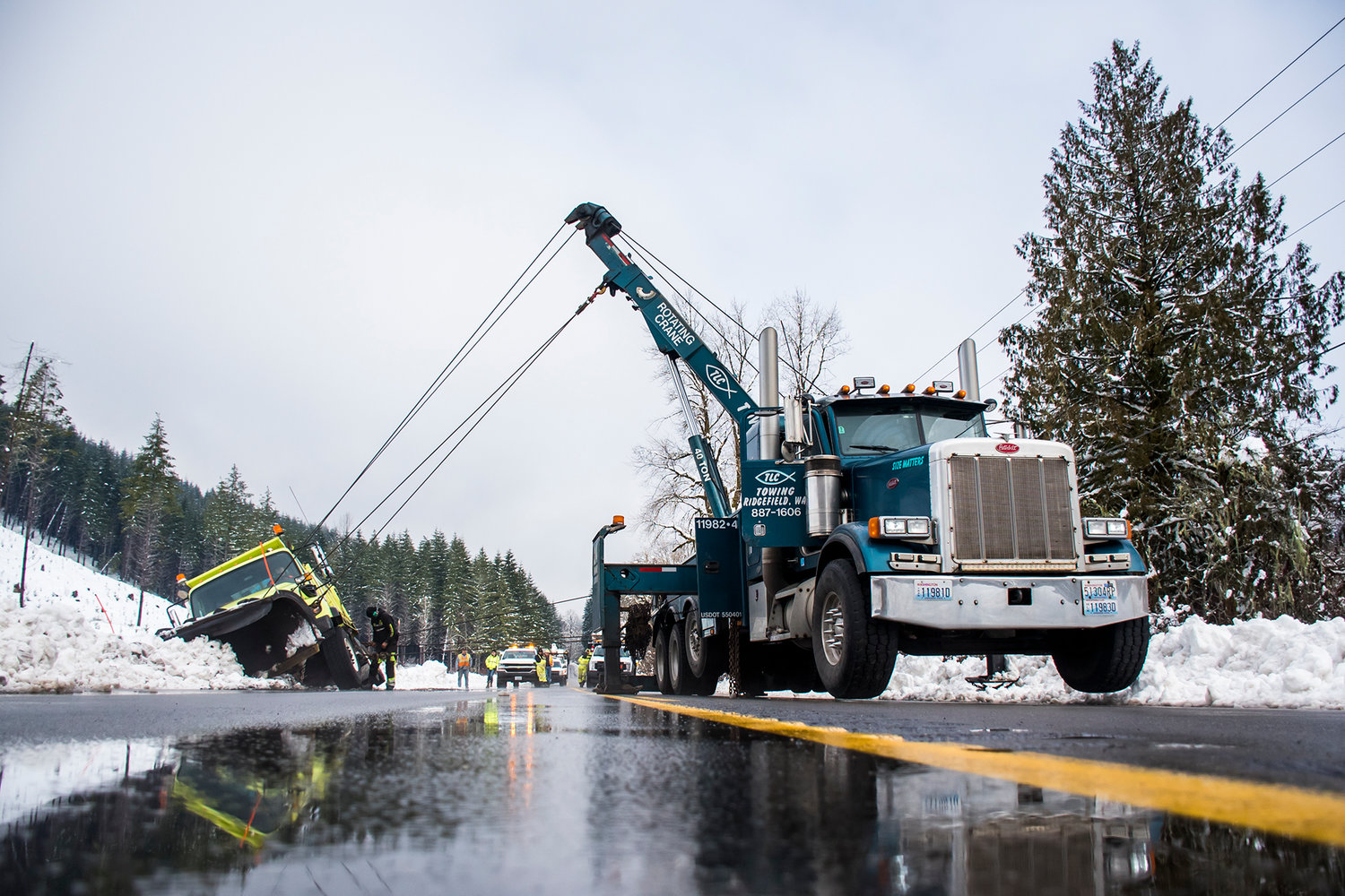 A snow plow is seen hoisted up with a crane after tipping while clearing roads along State Route 7 Wednesday morning between Morton and Mineral.