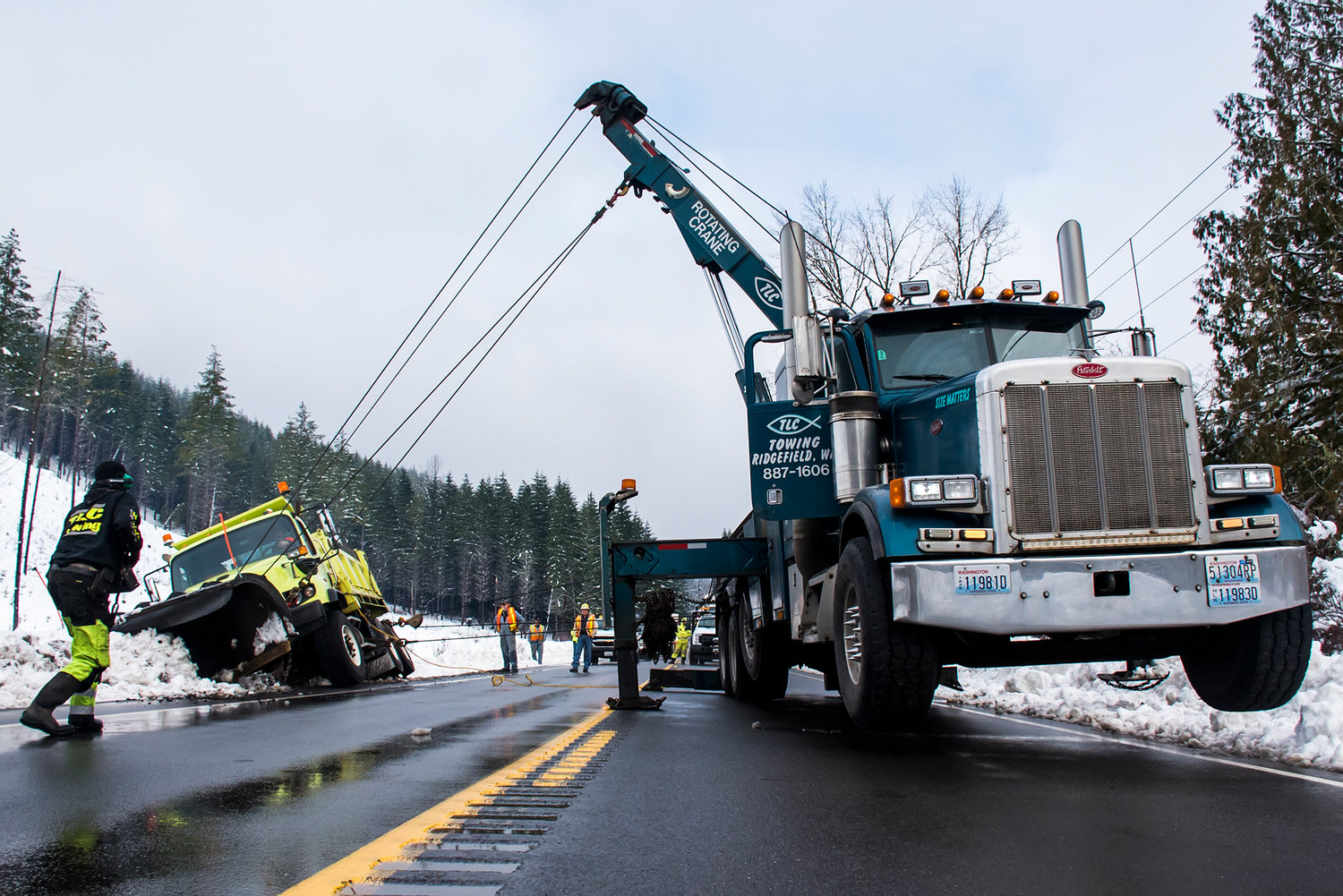 A snow plow is seen hoisted up with a crane after tipping while clearing roads along State Route 7 Wednesday morning between Morton and Mineral.