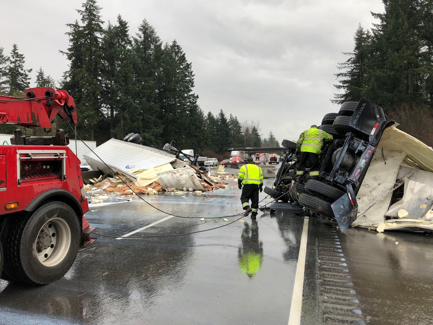 Crews hook chains from a tow truck to an overturned semi truck that blocked all southbound lanes of I-5 near Tumwater Wednesday morning.
