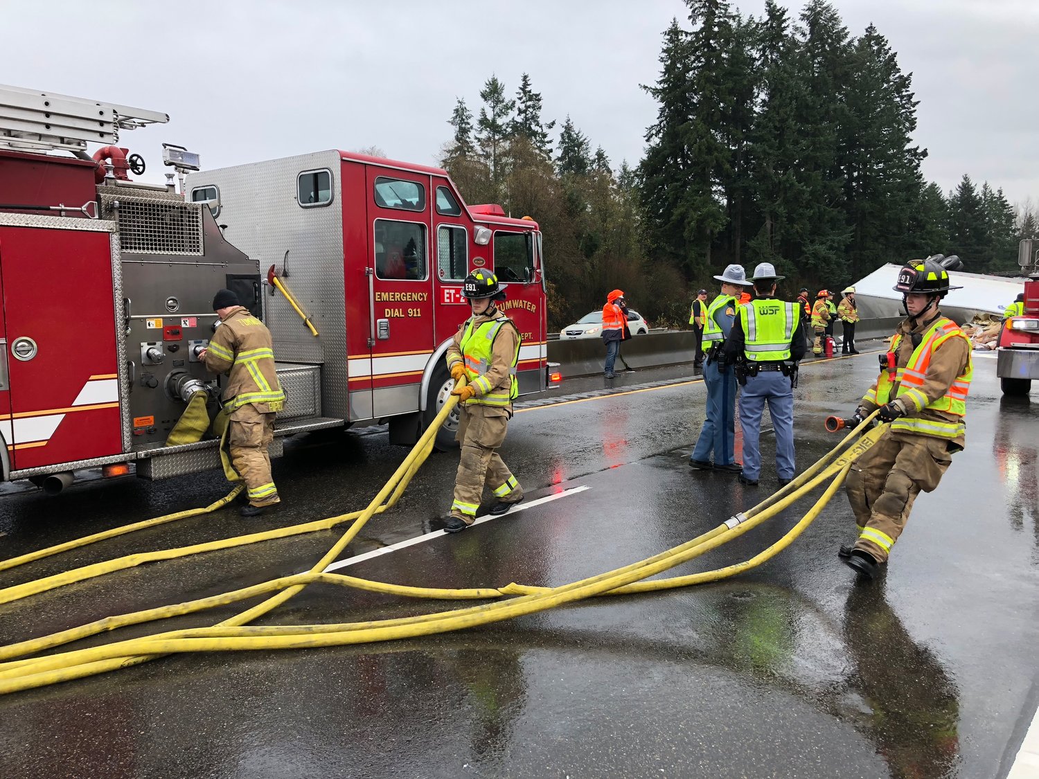 Fire crews roll out a hose as a precaution after an overturned semi truck that blocked all southbound lanes of I-5 traffic started smoking Wednesday morning.