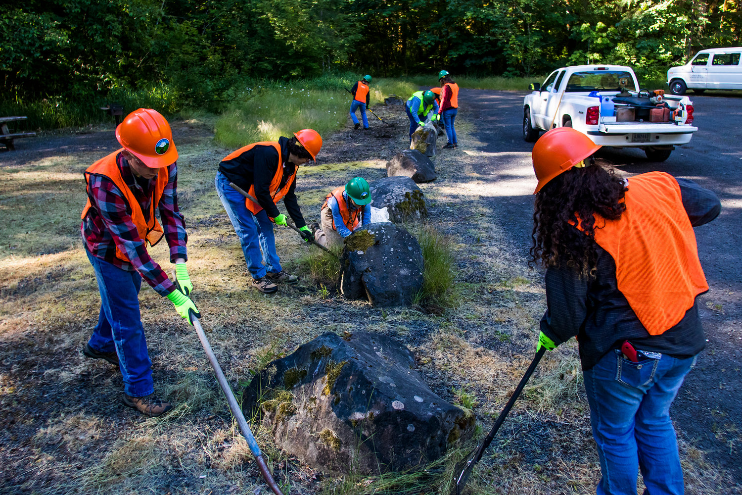 Members of the Discovery Team clean up debris and natural material surrounding rocks and park benches at the Woods Creek Trailhead Wednesday afternoon in the Gifford Pinchot National Forest.