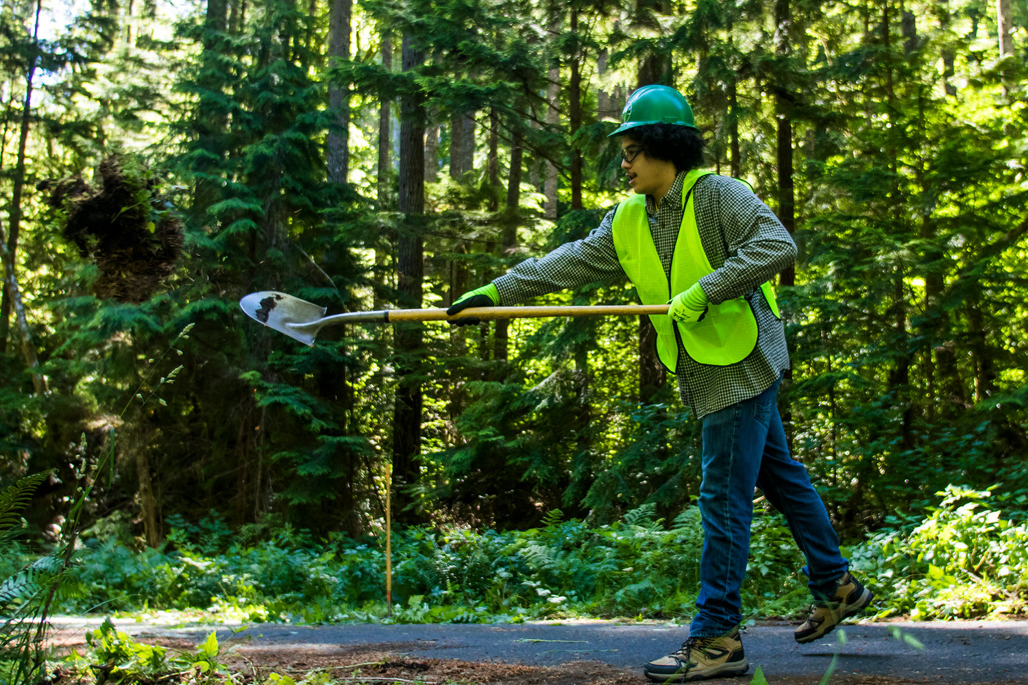 Adam Mommer, a senior at White Pass High School, uses a shovel to move natural materials away from Forest Road 77 Wednesday afternoon in the Gifford Pinchot National Forest.