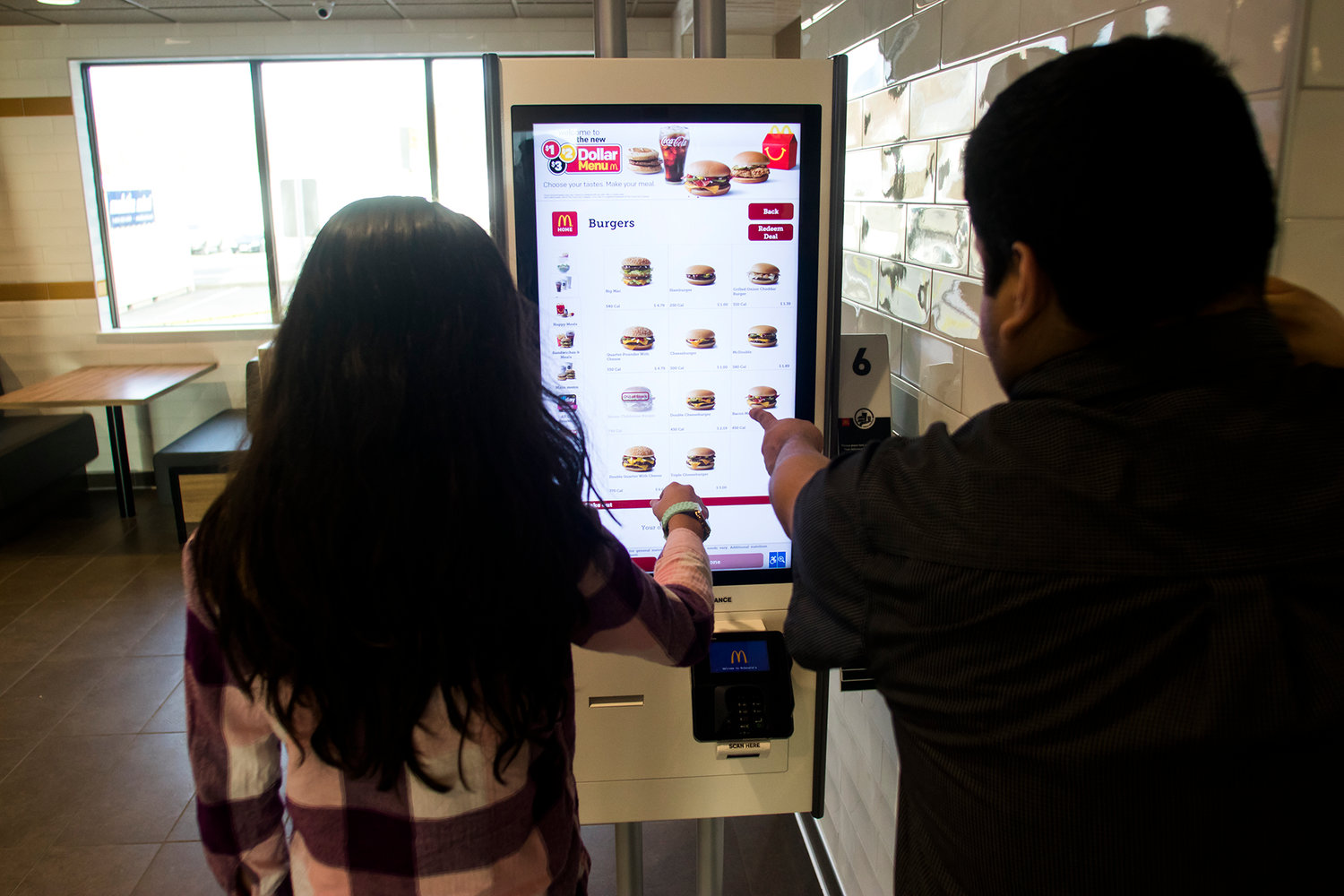 Rene Valdez, right, assistant manager at McDonald's, helps Cece Velazquez, left, order on the new touch-screen kiosk in the newly remodeled McDonald's Monday afternoon in Chehalis.