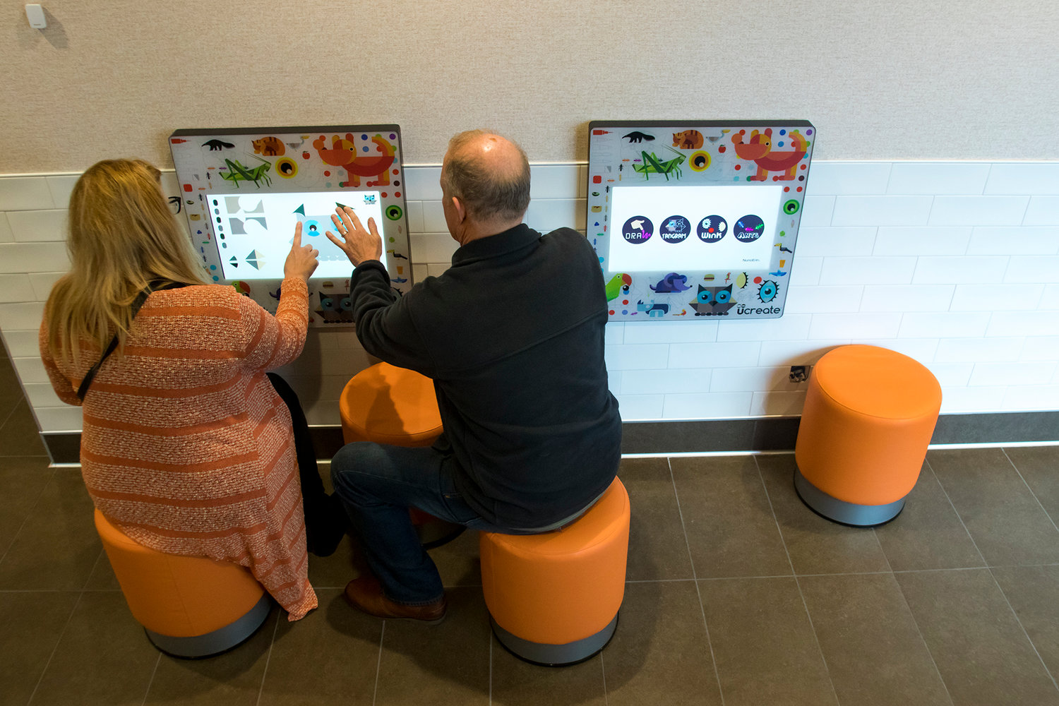 Mathew Neal, right, and his wife Kimberley Neal, left, play on the new 'Kids Play' interactive game pads in the newly remodeled McDonald's Monday afternoon in Chehalis.