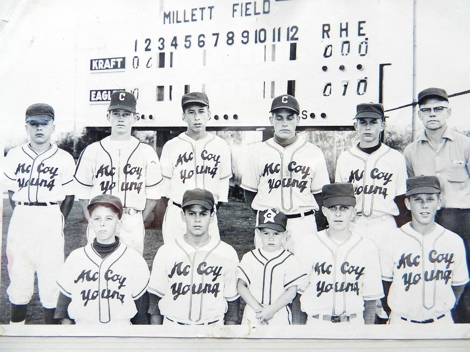 Millett Field scoreboard is visible in the background of this youth baseball team photo.