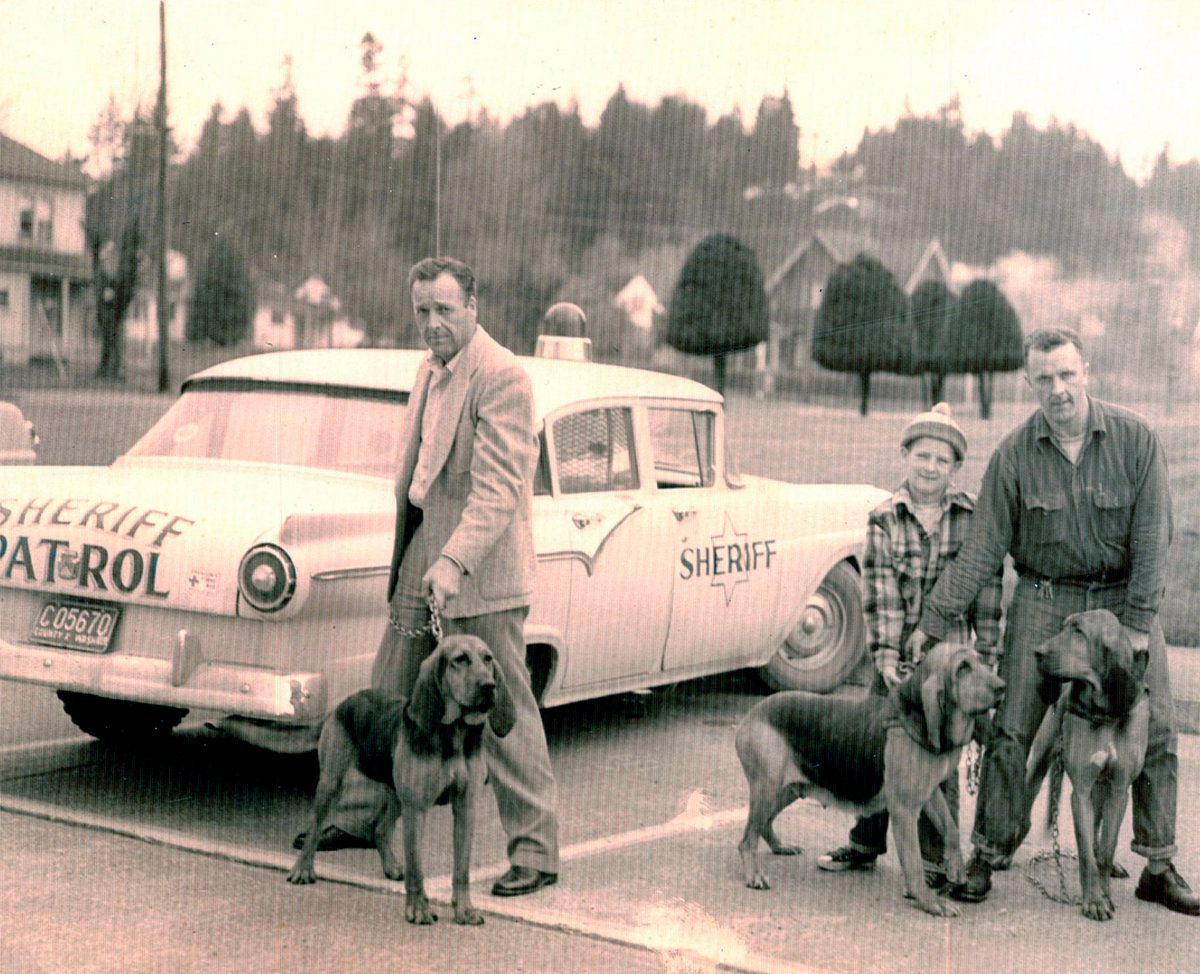 Lewis County Sheriff Bill Wiester Sr., right, and his son, future Grant County Sheriff Bill Wiester Jr., are joined by Undersheriff Tom Cooper in this photo with three of Wiester Sr.'s bloodhounds.