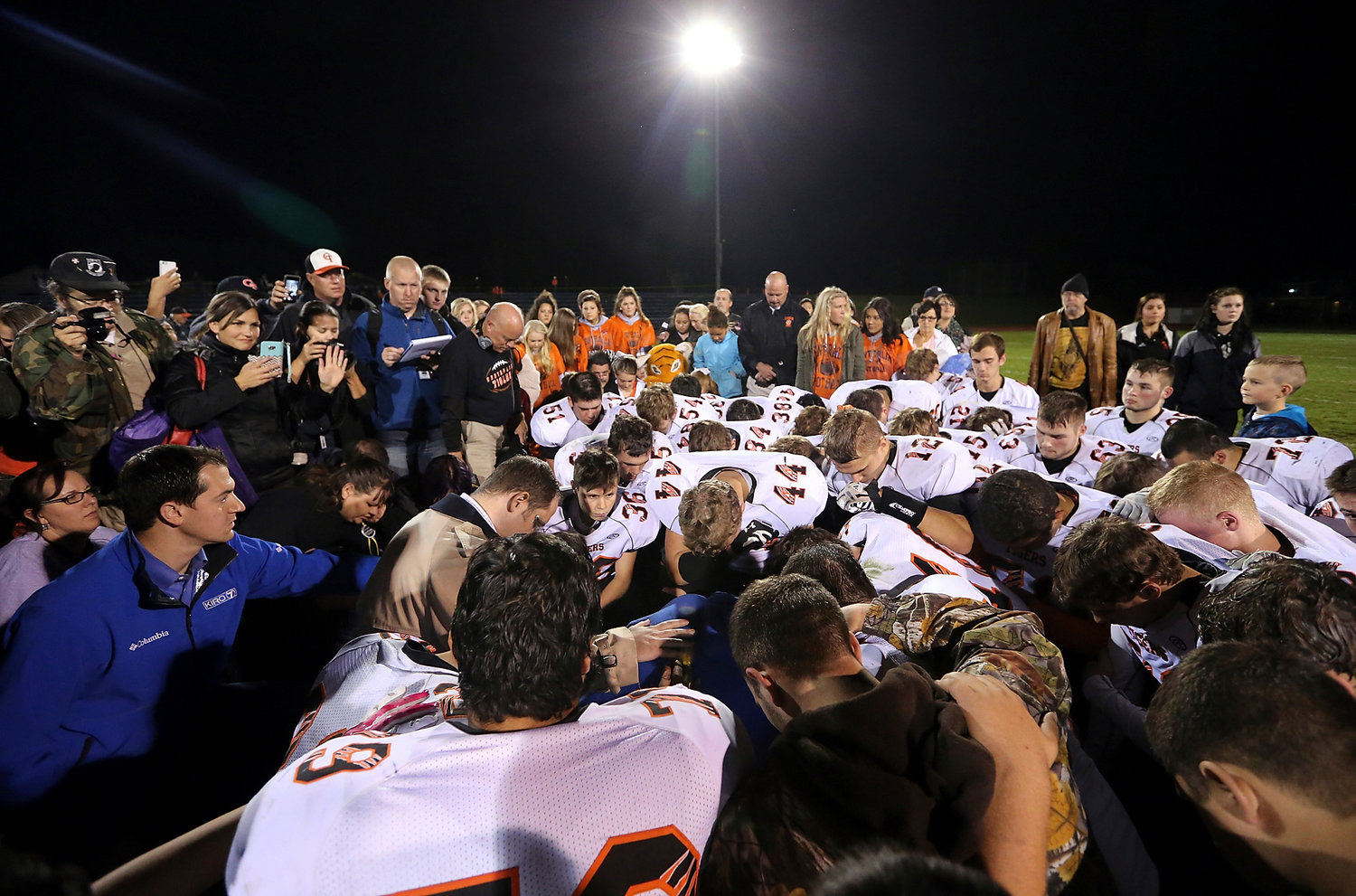 In this Friday, Oct. 16, 2015, photo, former Bremerton assistant football coach Joe Kennedy, obscured at center in blue, is surrounded by Centralia players after they took a knee with him and prayed after their game against Bremerton, in Bremerton, Wash. 