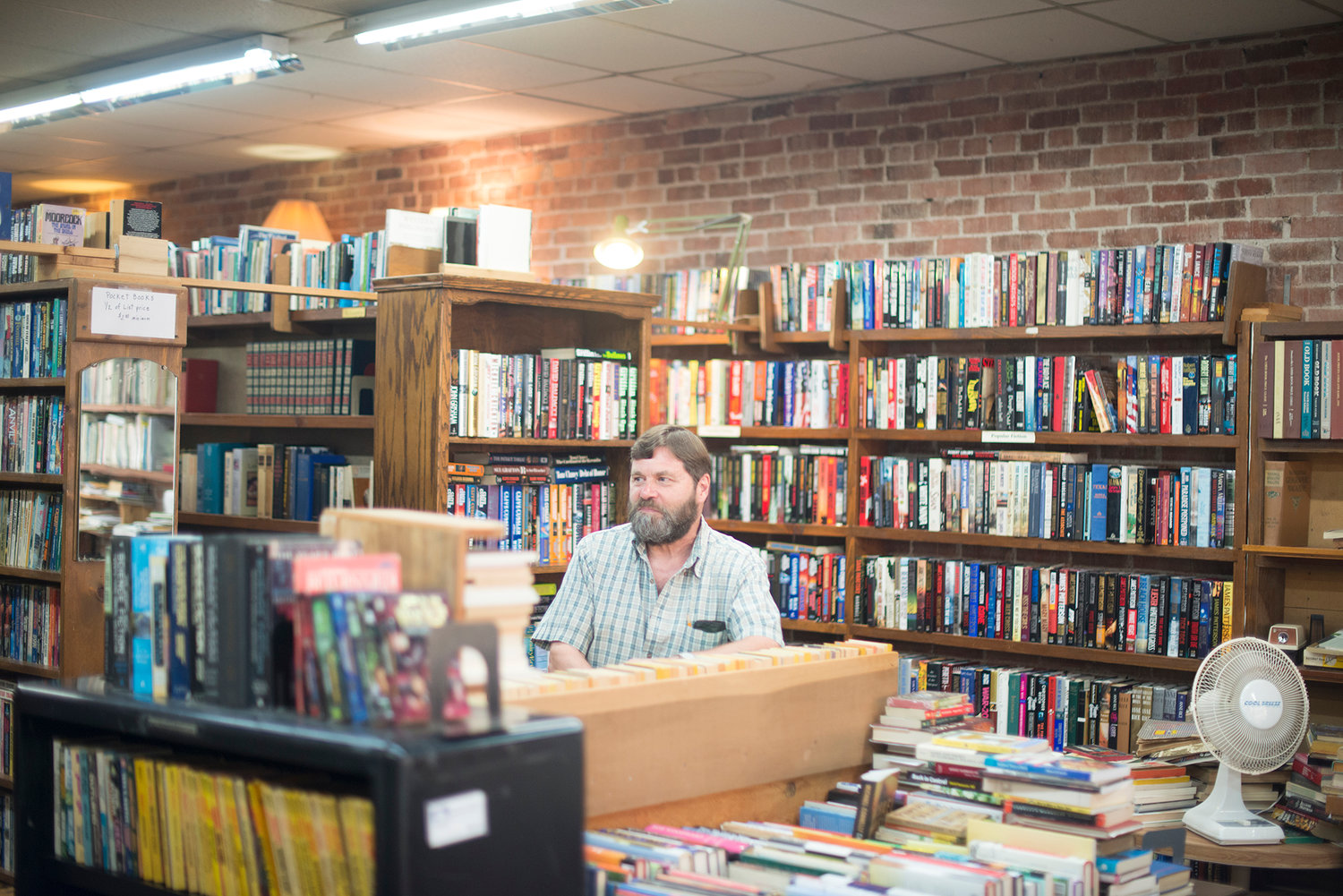 Owner of Tilikum Books Geary Lockard talks to a customer in his bookstore on Wednesday. He said interacting with people is his favorite part of running the store.