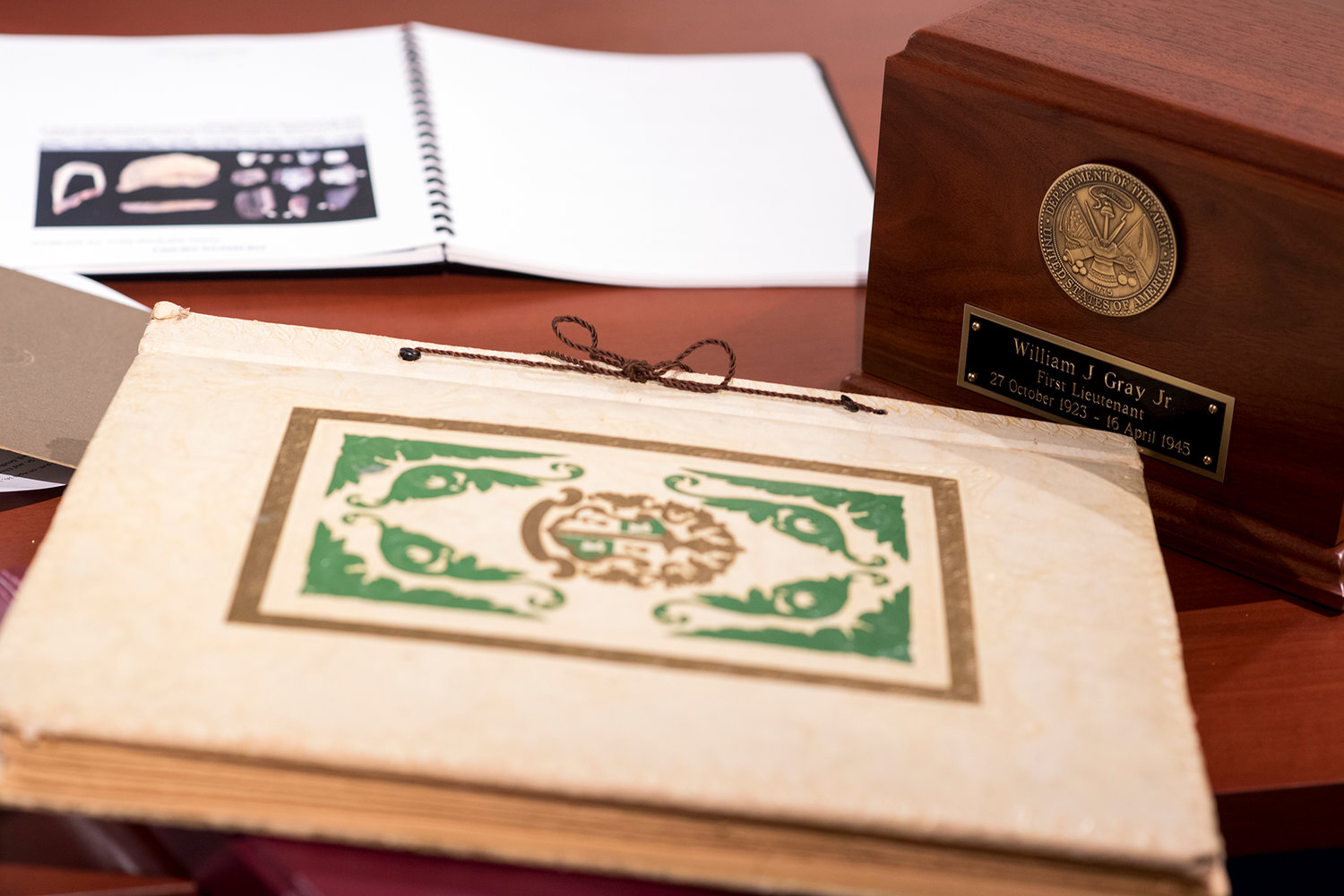 The recently discovered scrapbook containing letters, telegrams and pictures from Army Air Force 1st Lt. William "Bill" James Gray, Jr. sits on a table with an urn that will hold his remains and a forensic anthropology report authored by the the Defense POW/MIA Accounting Agency.