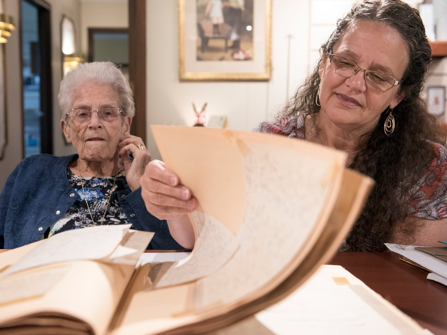 Jeanne Louvier, left, looks on as her daughter, Jan Bradshaw, flips through a scrapbook compiled by Louvier’s mother of her son’s correspondence while serving in Europe during World War II. His remains were found last year and will be buried during a funeral with full military honors Friday, July 14. 
