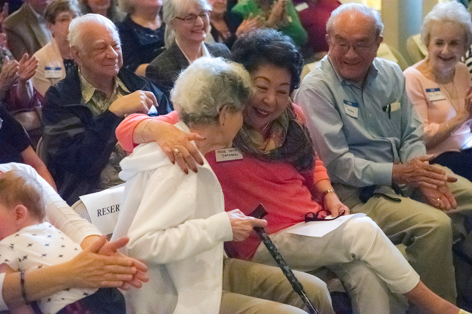 Irene (Sato) Yamasaki, center, who grew up in Adna and was 18 months old when the train left Chehalis for Tule Lake, hugs long time friend Doris Hastings on Saturday during the dedication of the Japanese internment plaque at the Lewis County Historical Museum. Yamasaki served as a flower girl at Hastings’ wedding in the 1950s.