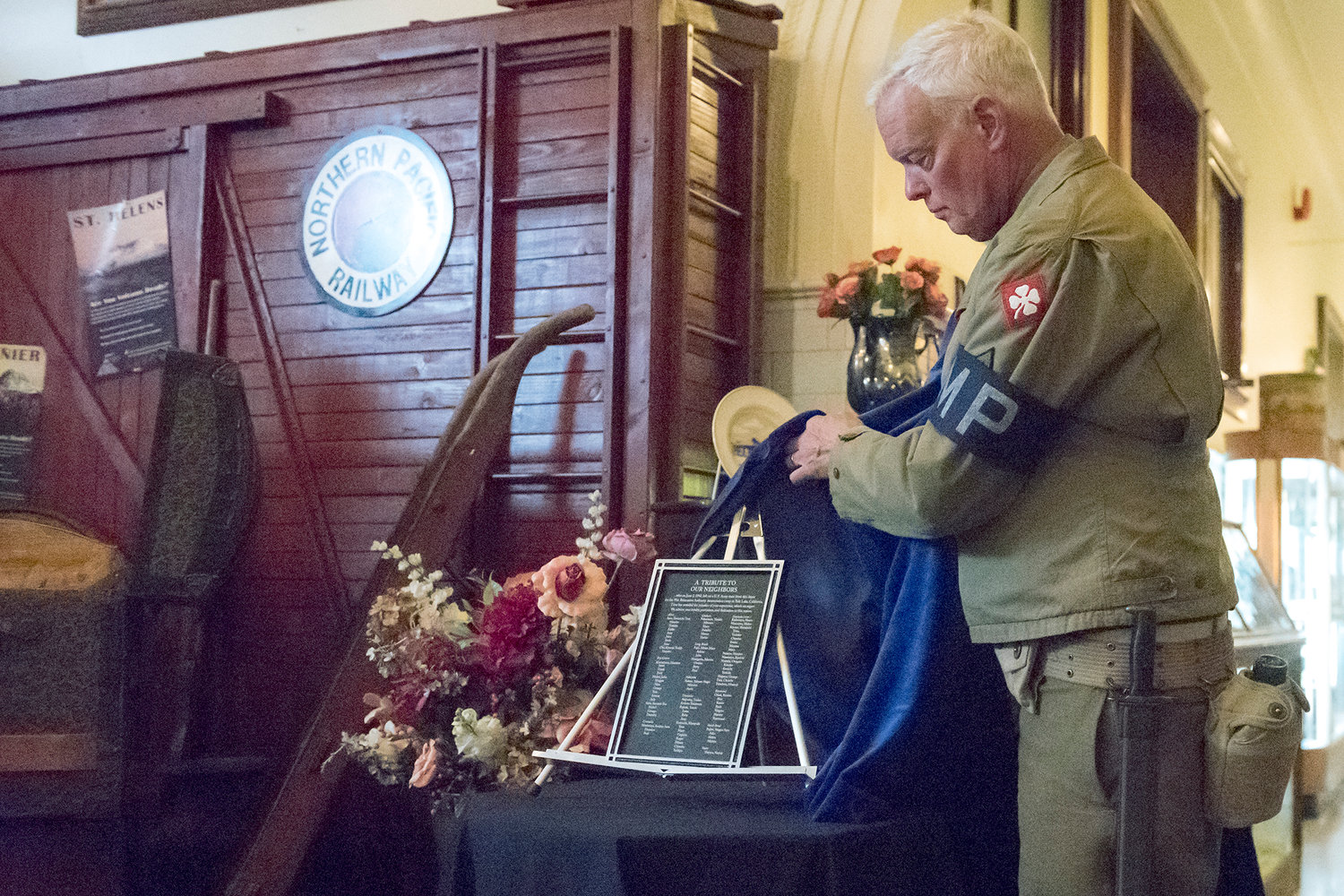 President of the Lewis County Historical Society Peter Lahmann unveils the remembrance plaque dedicated to the Japanese Americans who left Chehalis for Tule Lake California on June 2, 1942. He is dressed in an authentic World War II Army uniform. The patch on his arm is from the 4th Army which was charged with the internment process.