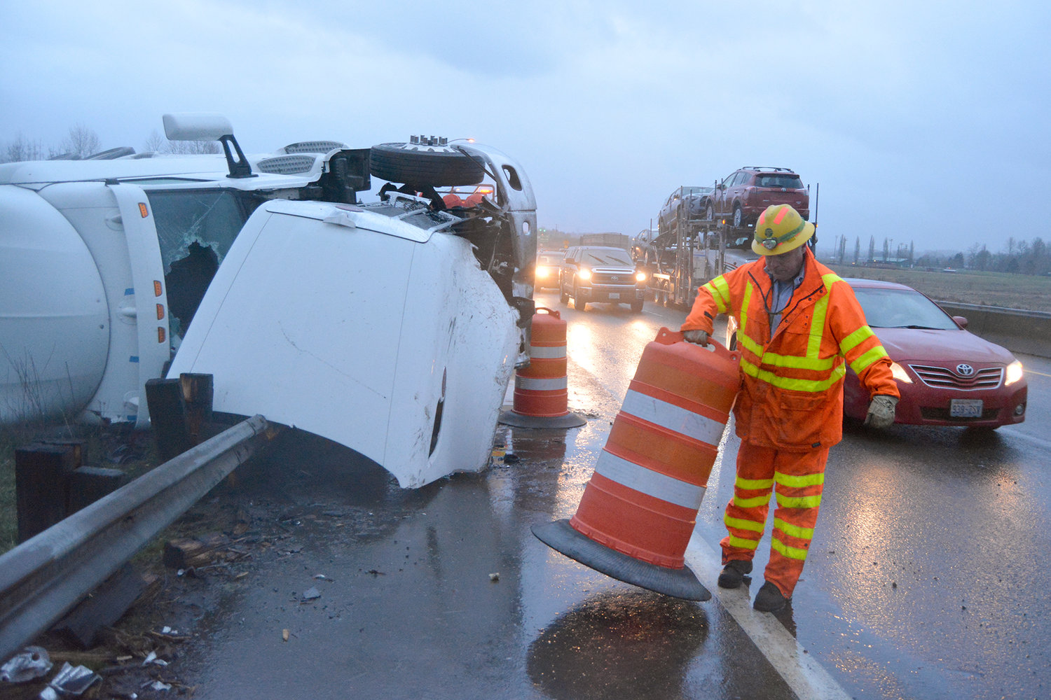 A Washington State Department of Transportation employee puts out road barricades alongside a semi truck that turned onto its side on the northbound lane of Interstate 5 at mile post 76 on Tuesday morning in Chehalis.