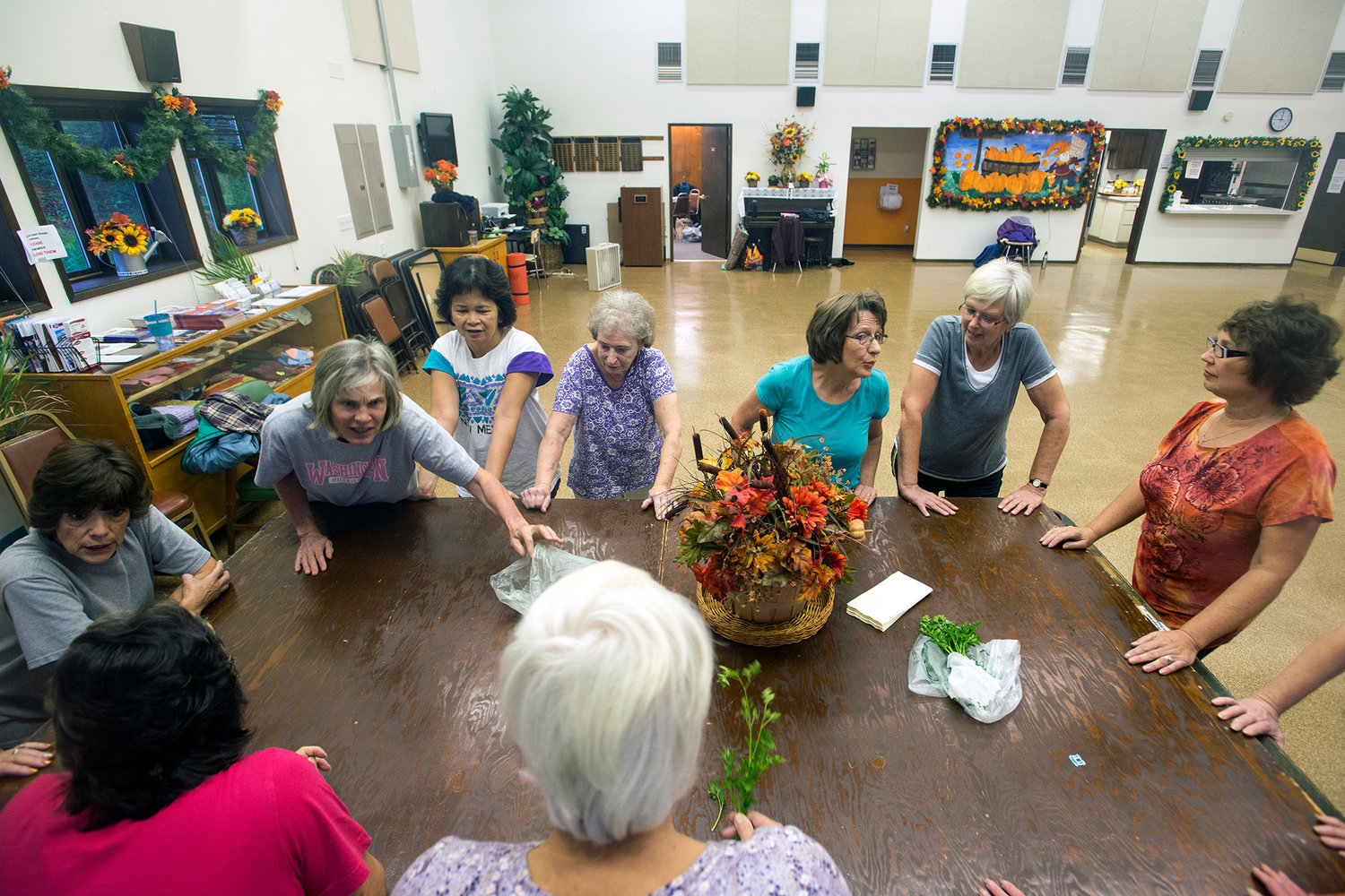 Women chatted about freshly picked herbs that were brought in to share as they took a break to stretch prior to starting the aerobic portion of the Toledo Senior Center's women's exercise class in October 2014.