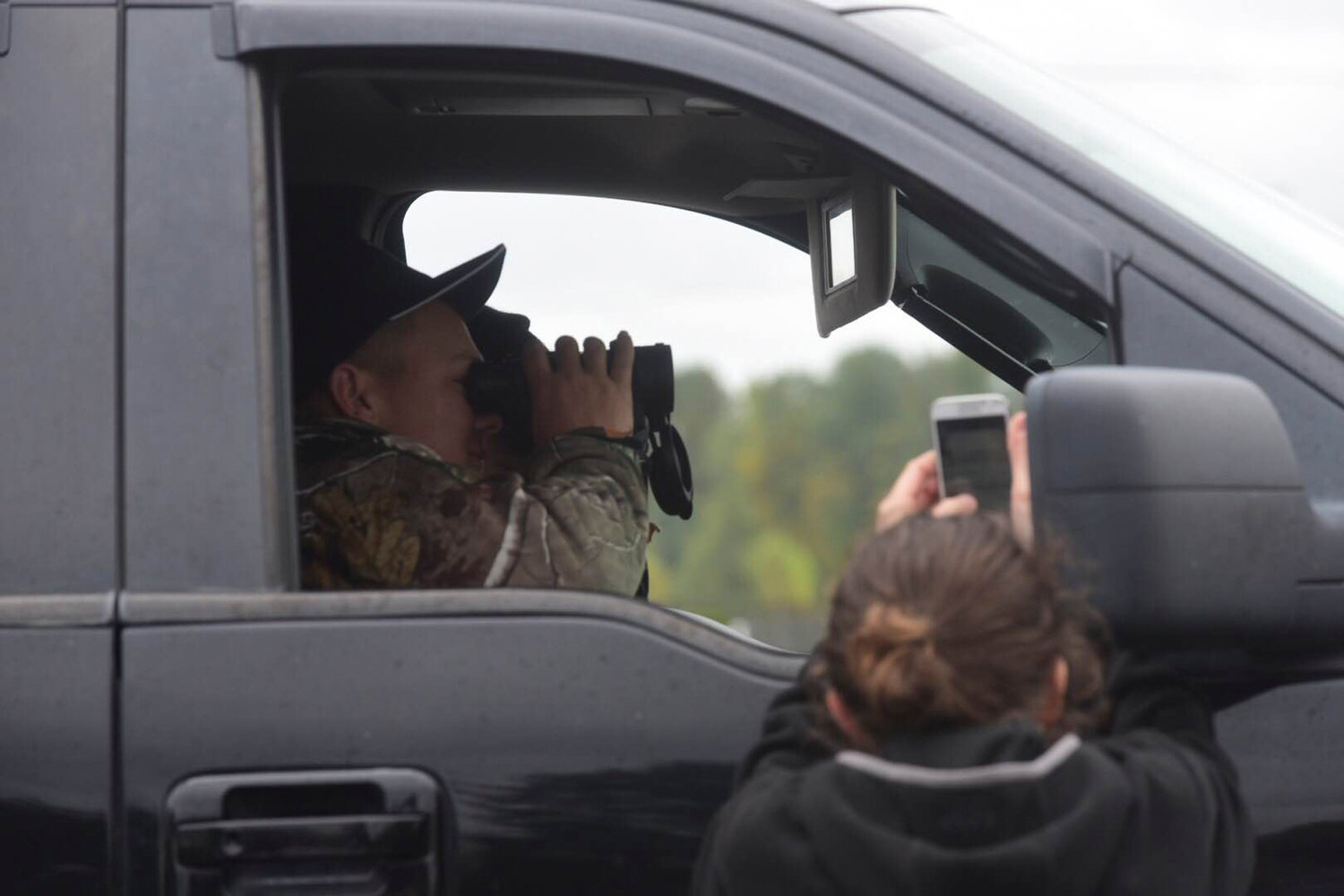 A person waiting for information on the Centralia High School lockdown uses binoculars to get a closer look while in his vehicle at the Community Church of God across from the high school. 