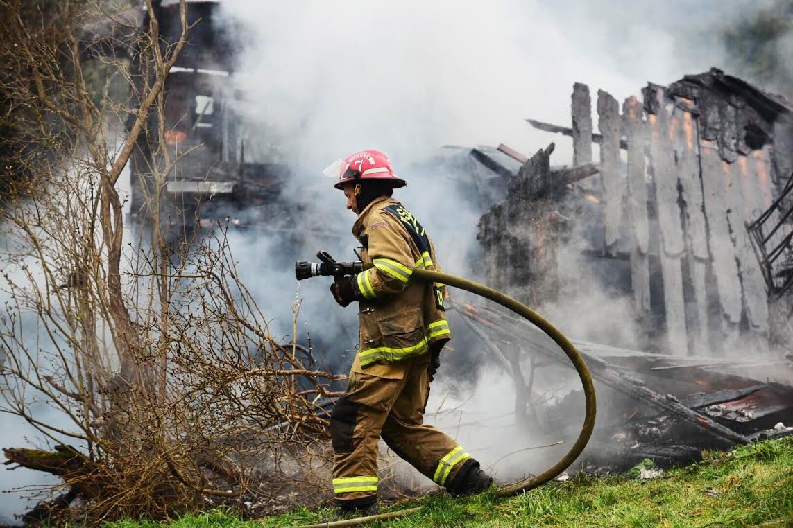 A firefighter continues efforts to control heavy smoke from a fire that destroyed a house in Winlock Thursday morning. Three people are feared dead in the blaze.
