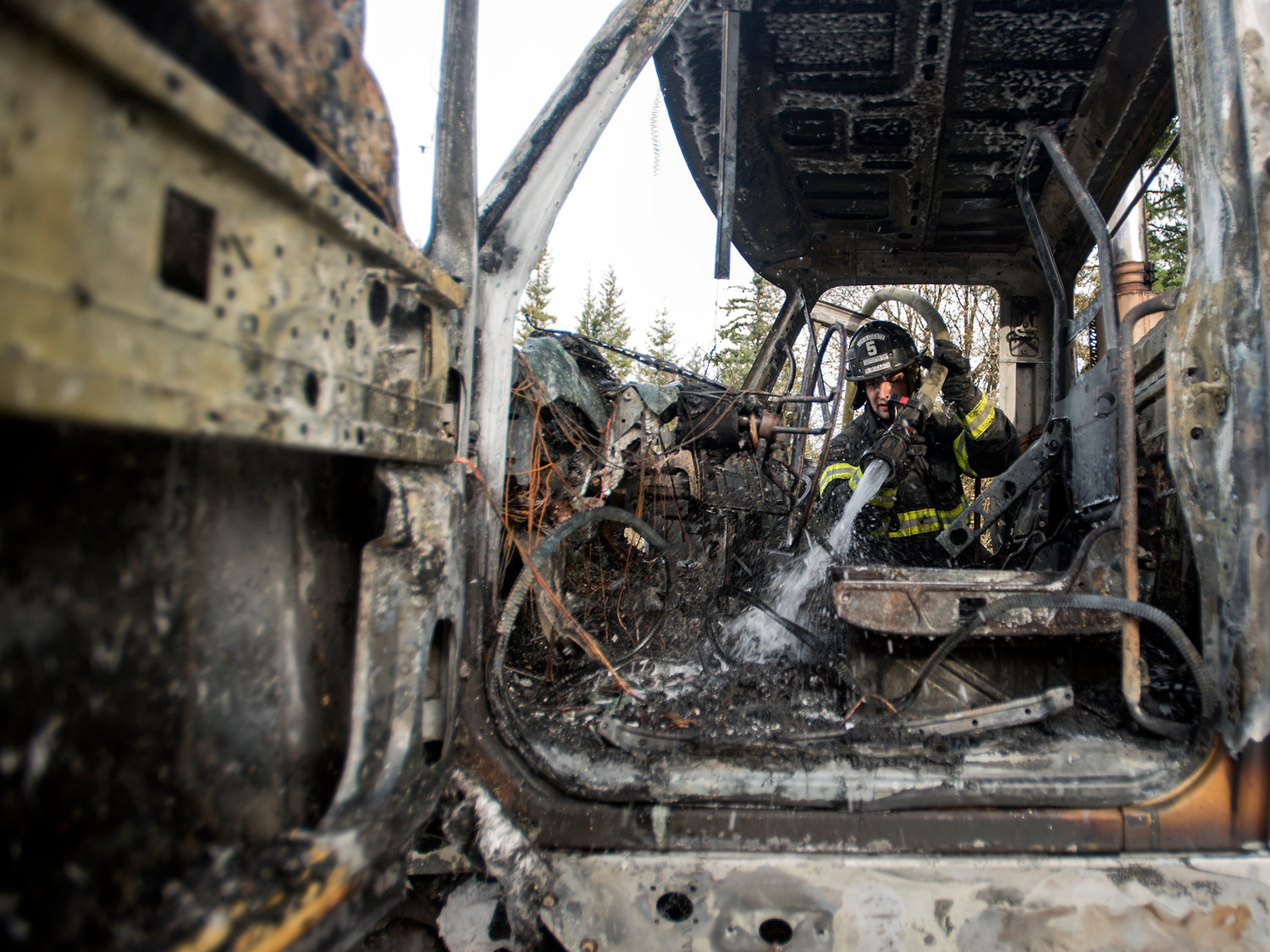 Lewis County District No. 5 firefighter, Brad Bozarth, puts out hot spots inside the cab of a semi truck that caught fire while driving north on Interstate 5 near exit 71 in Napavine on Tuesday afternoon. No injuries were reported in the incident.