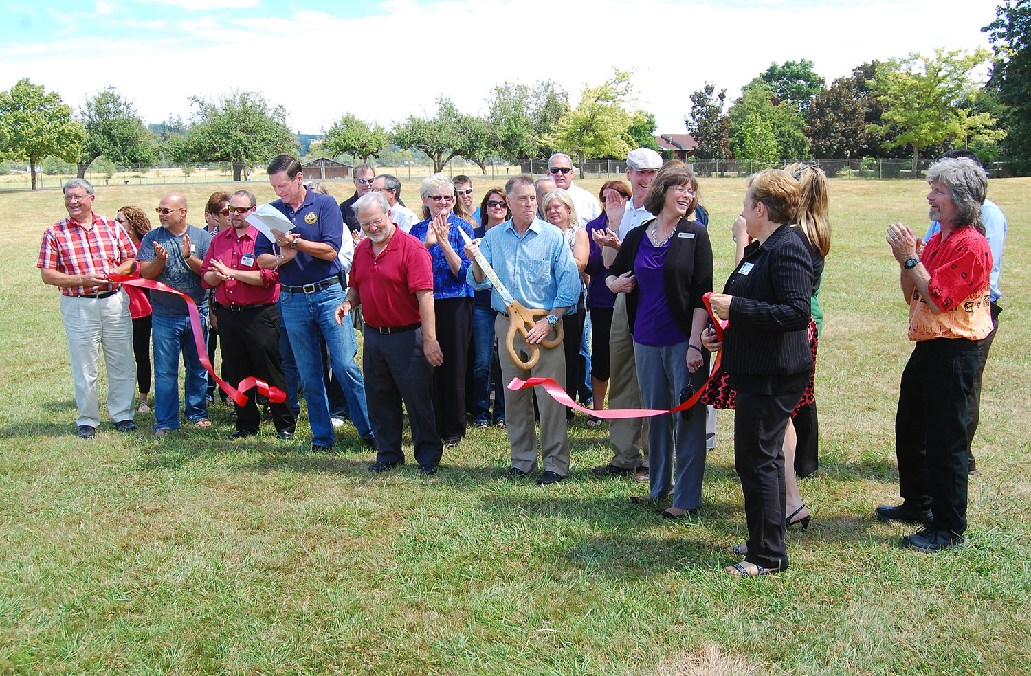 Civic leaders and members of the Centralia-Chehalis Chamber of Commerce applaud after former Chehalis Mayor Tony Ketchum cuts a ribbon at Stan Hedwall Park Monday afternoon.