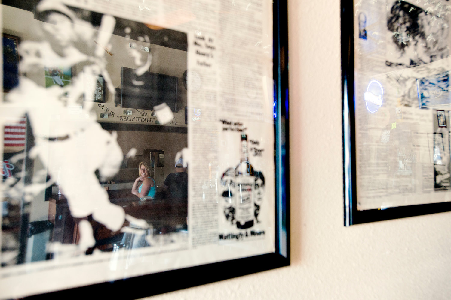 Marianne Viggers is seen in the reflection of a framed newspaper sports page featuring Hank Aaron's famous 715th home run which was donated by a local patron.