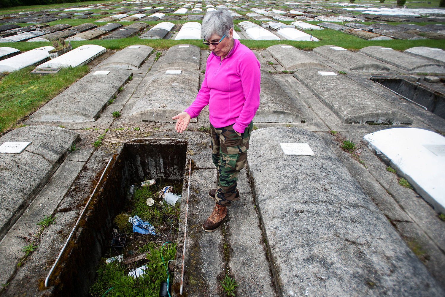 Jennifer Duncan, a former caretaker at Greenwood Memorial Park, shows trash in an open concrete burial plot at the Centralia cemetery in April 2014. 