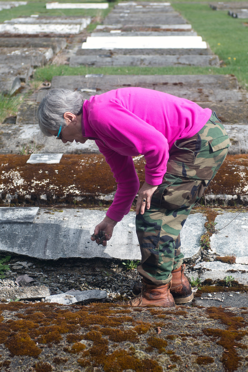 Jennifer Duncan, a caretaker at Greenwood Cemetery, picks up crumbled cement from a surface burial vault at the Centralia cemetery off of Reynolds Road on Wednesday morning.