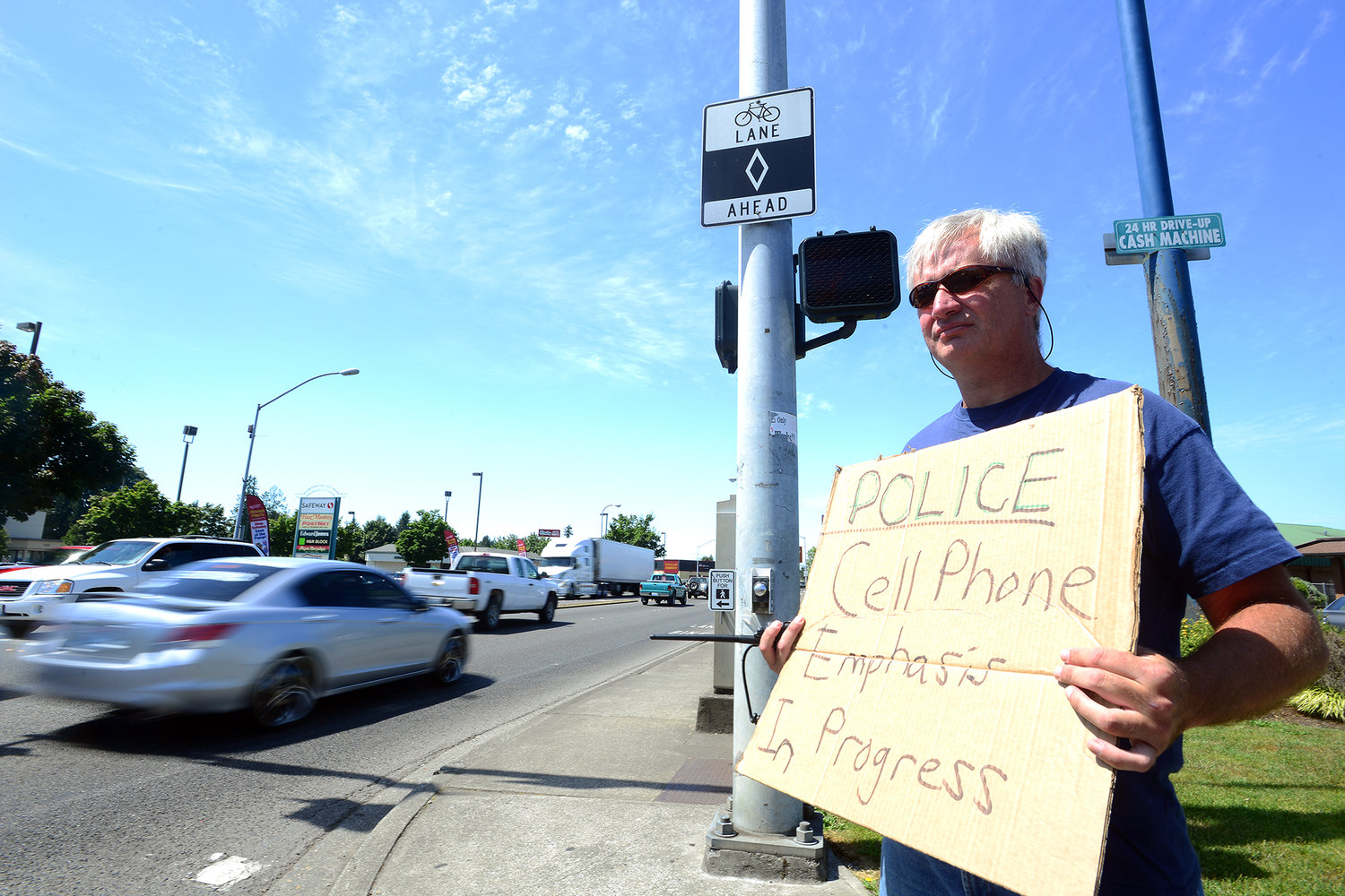 Centralia Police Sgt. Jim Shannon holds a sign informing drivers of a cell phone enforcement procedure taking place near the corner of Harrison Avenue and Belmont Avenue in August 2013. 