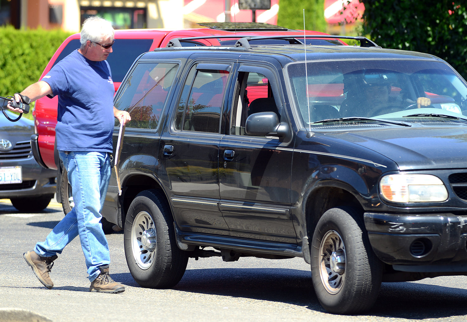 FILE PHOTO — While holding a sign that reads "Police Cell Phone Emphasis in Progress," former Centralia Police Sgt. Jim Shannon walks up to a driver talking on his cell phone while parked at a red light on Bellmont Avenue in Centralia in August 2013.