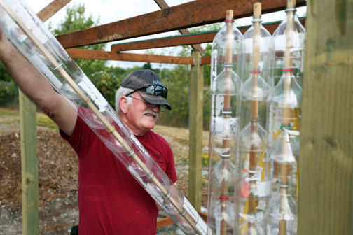 Chehalis resident Bob Taylor, president of the Lewis County WSU
Extension Master Recyclers, and a master composter, helps to
construct a greenhouse made largely out of empty 2-liter pop
bottles at the Centralia Transfer Station Monday. Taylor estimated
that the cost for the entire greenhouse did not exceed $100 because
of the recycled materials and volunteer labor. More pop bottles are
being sought to finish the project.