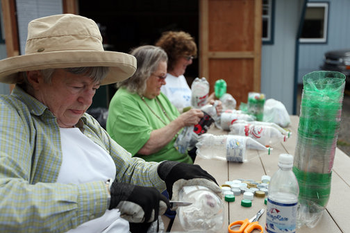 Volunteers Alice Fisher (left), Mary White (center) and Shawn
Hill prepare 2-liter bottles Monday to be used for a greenhouse
made largely out of recycled materials at the Centralia Transfer
station.