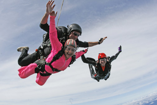 Heather Bodin, wearing a pink jumpsuit, soars through the air with her tandem instructor, Brett Martin, and Valinda Mitchell, another lupus victim, during the Leap for Lupus at the Shelton airport Aug. 2.