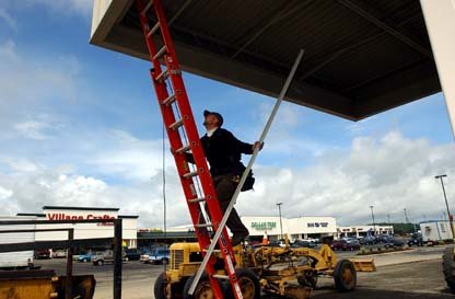 Gary J. Cichowski / The Chronicle R. J. Mazza climbs a ladder to attach a piece of trim to the drive-through section of the new branch of Security State Bank at the Twin City Town Center west of Interstate 5 in Chehalis Friday afternoon.