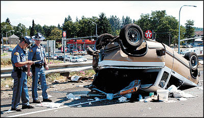 Chronicle File Photo Washington State Patrol Troopers James Zane and Neil Weaver, Chehalis, note details of a rolled-over pickup truck near exit 81 on northbound Interstate 5 in Centralia. Four vehicular homicide charges have been lodged against a Tacoma trucker in connection with the August incident.